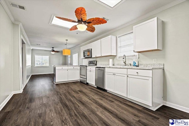 kitchen featuring appliances with stainless steel finishes, dark wood-style flooring, a peninsula, white cabinetry, and a sink