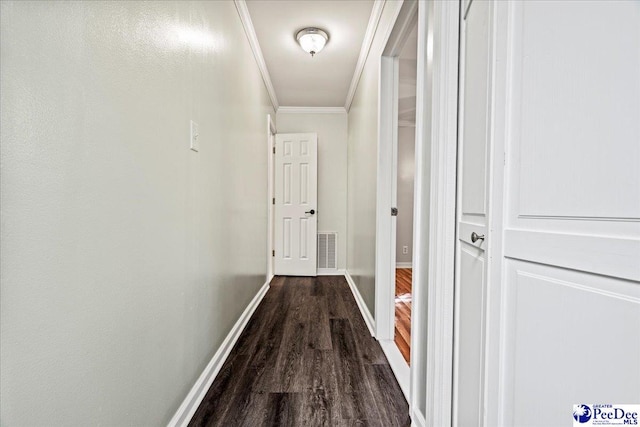 hall featuring dark wood-style floors, baseboards, visible vents, and crown molding