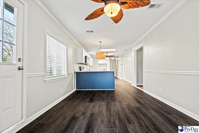 kitchen with a peninsula, dark wood-type flooring, a ceiling fan, visible vents, and crown molding