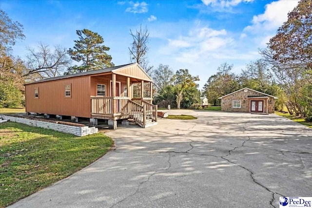 view of side of home with covered porch, concrete driveway, and a yard