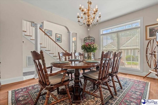 dining area featuring a chandelier, baseboards, light wood-style flooring, and stairs