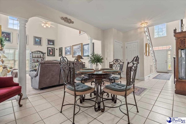 dining space with decorative columns, light tile patterned floors, healthy amount of natural light, and a towering ceiling