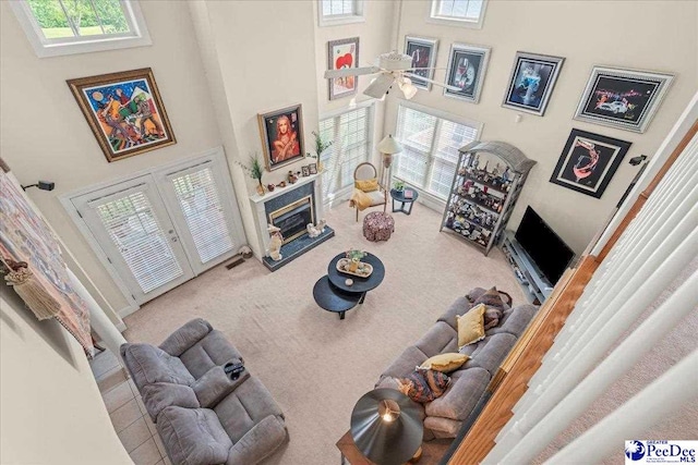 living room featuring a high ceiling, carpet, a glass covered fireplace, and french doors