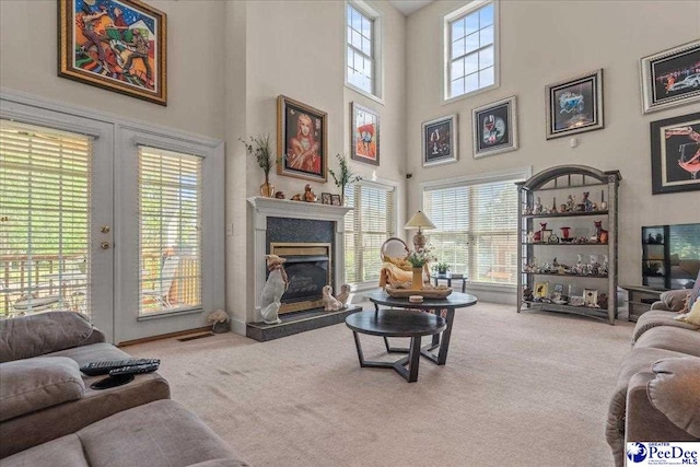 living area with carpet floors, a high ceiling, and a fireplace with raised hearth