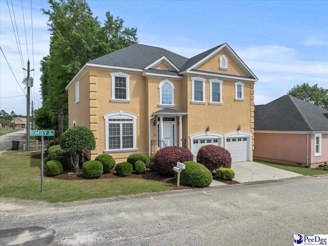 view of front of home with concrete driveway, an attached garage, and stucco siding
