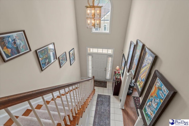 entryway with a chandelier, light tile patterned floors, a high ceiling, and stairway