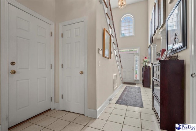 entryway featuring light tile patterned flooring, baseboards, and a high ceiling