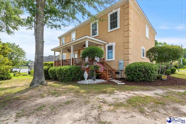 view of front of property featuring ceiling fan, covered porch, stairs, and stucco siding