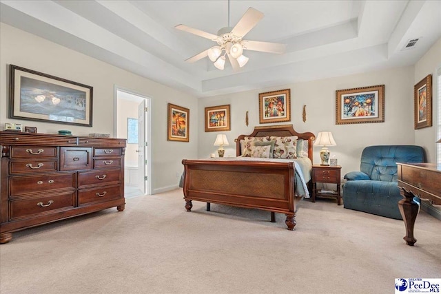 bedroom with a raised ceiling, light carpet, a ceiling fan, ensuite bath, and baseboards