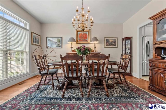 dining space with a chandelier, baseboards, and light wood finished floors