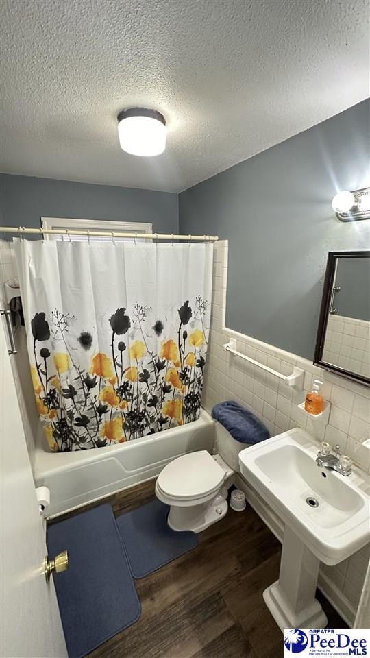 bathroom featuring shower / tub combo with curtain, tile walls, hardwood / wood-style floors, a textured ceiling, and toilet