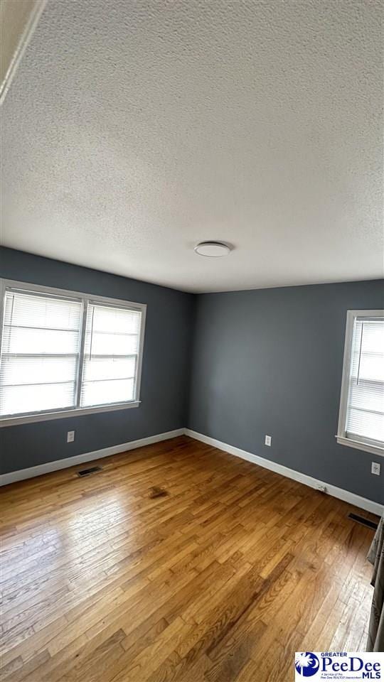 empty room with light hardwood / wood-style floors and a textured ceiling