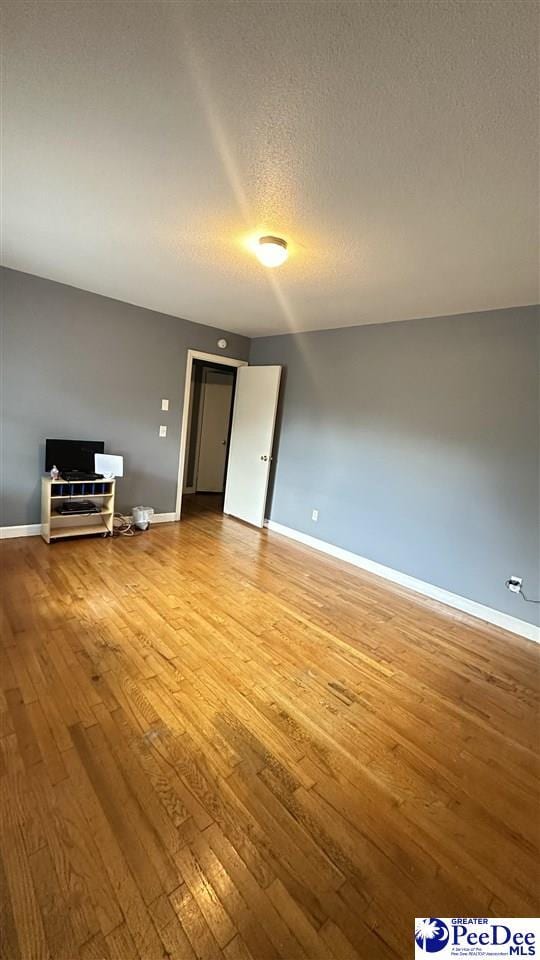 unfurnished living room with hardwood / wood-style flooring and a textured ceiling