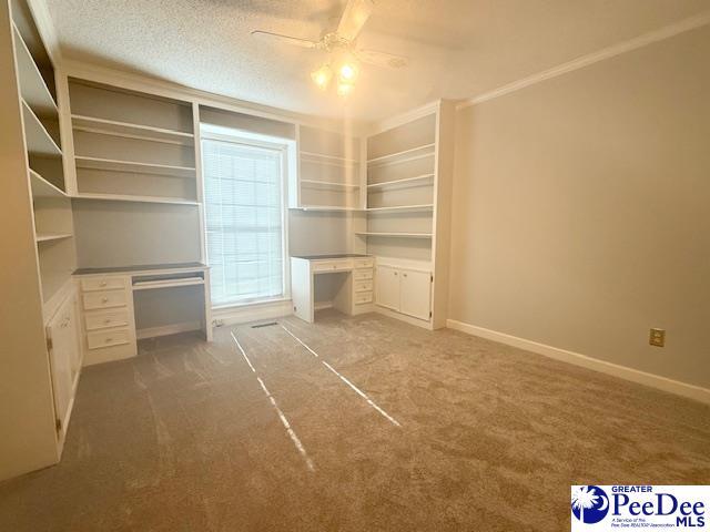 unfurnished bedroom with carpet, baseboards, built in desk, and a textured ceiling