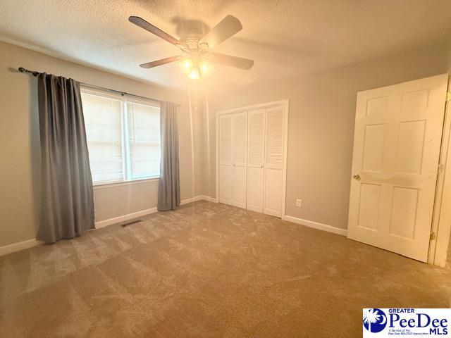 unfurnished bedroom with a textured ceiling, a closet, carpet, and baseboards