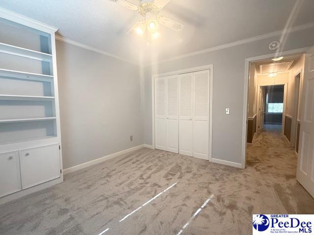 unfurnished bedroom with attic access, crown molding, and baseboards