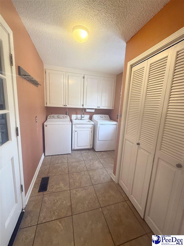 laundry room featuring a textured ceiling, baseboards, independent washer and dryer, cabinet space, and tile patterned floors