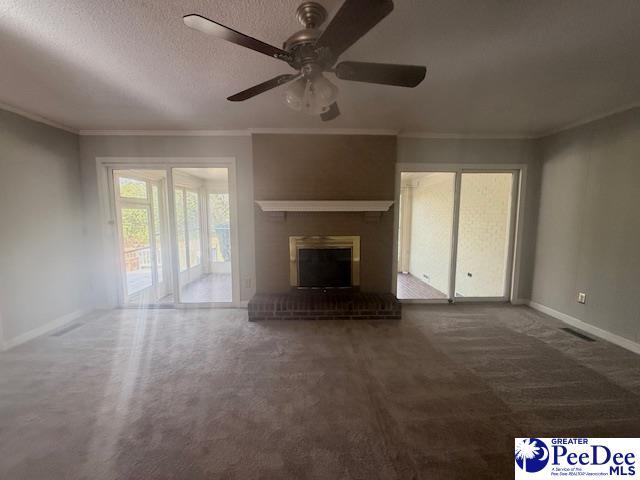 unfurnished living room featuring a textured ceiling, a fireplace, visible vents, and crown molding