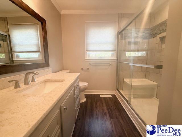 full bath with toilet, plenty of natural light, ornamental molding, and wood finished floors