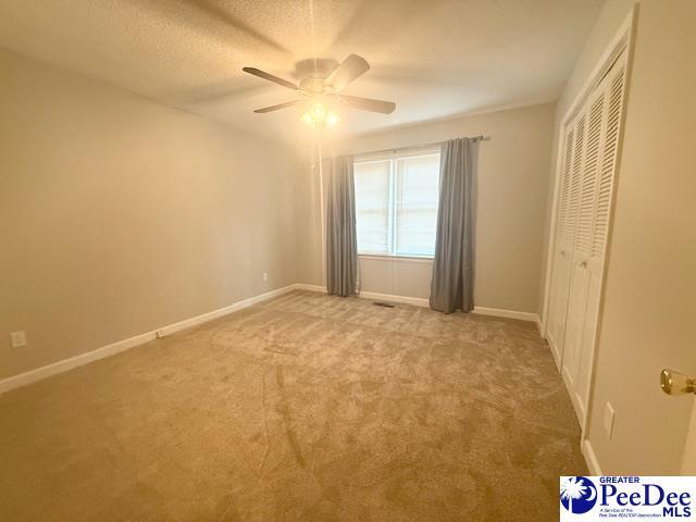 interior space with light carpet, a closet, baseboards, and a textured ceiling