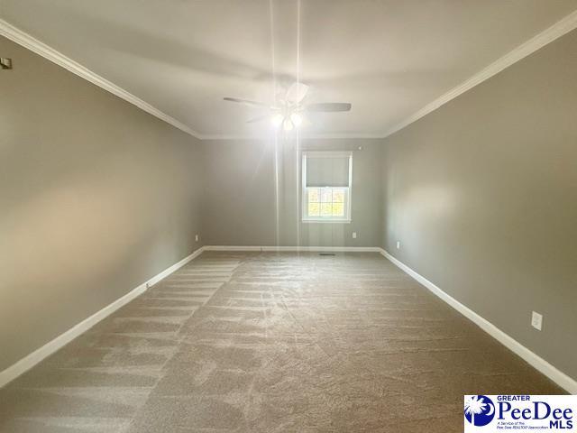 carpeted empty room with ornamental molding, ceiling fan, and baseboards