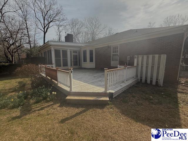 back of house featuring a sunroom, a chimney, and a deck