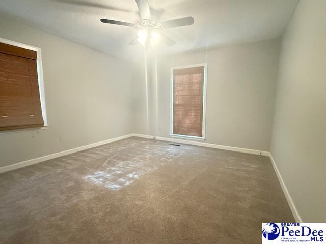 unfurnished room with carpet flooring, ceiling fan, and baseboards