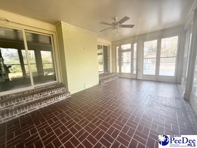 unfurnished sunroom featuring a ceiling fan