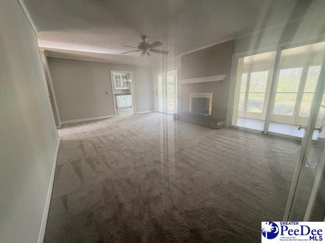 unfurnished living room featuring a fireplace with raised hearth, carpet, a ceiling fan, and baseboards