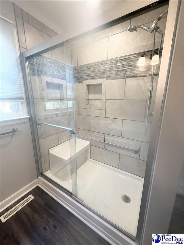 full bathroom with visible vents, a shower stall, baseboards, and wood finished floors