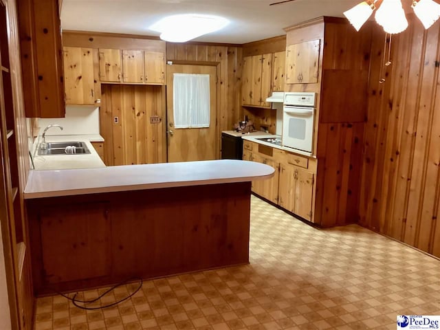 429 S Wallace Rd, Florence, SC 29506 - kitchen featuring kitchen peninsula, sink, white oven, and wood walls