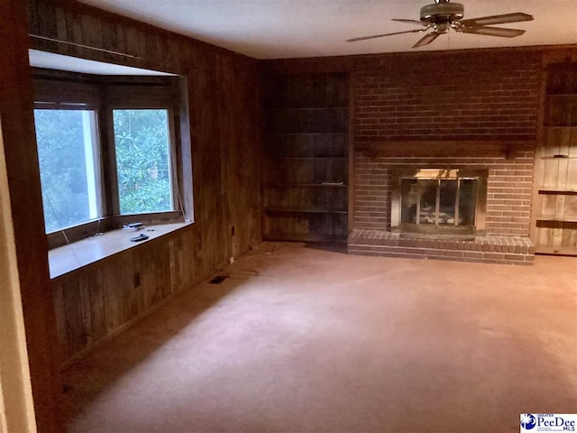 429 S Wallace Rd, Florence, SC 29506 - unfurnished living room with built in shelves, wood walls, a brick fireplace, carpet floors, and ceiling fan