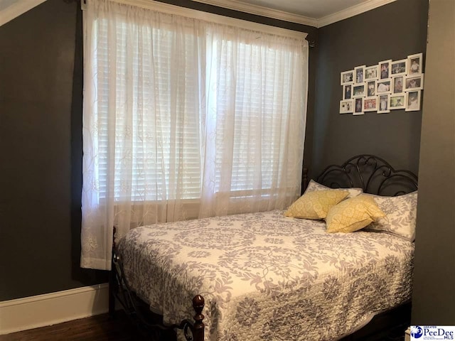 bedroom featuring hardwood / wood-style flooring, ornamental molding, and multiple windows