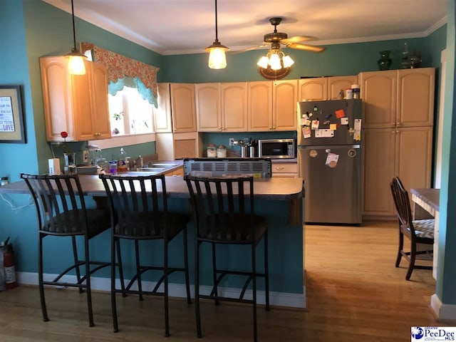 kitchen with hanging light fixtures, crown molding, stainless steel appliances, and a breakfast bar