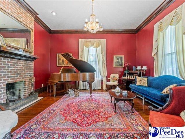 sitting room with an inviting chandelier, hardwood / wood-style flooring, a fireplace, and crown molding