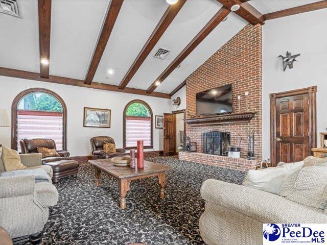 carpeted living room featuring a fireplace, high vaulted ceiling, and beamed ceiling