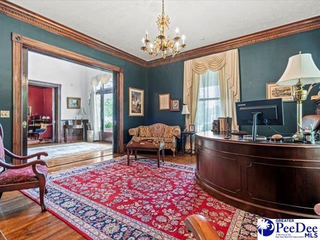 home office featuring hardwood / wood-style flooring, crown molding, a wealth of natural light, and a chandelier