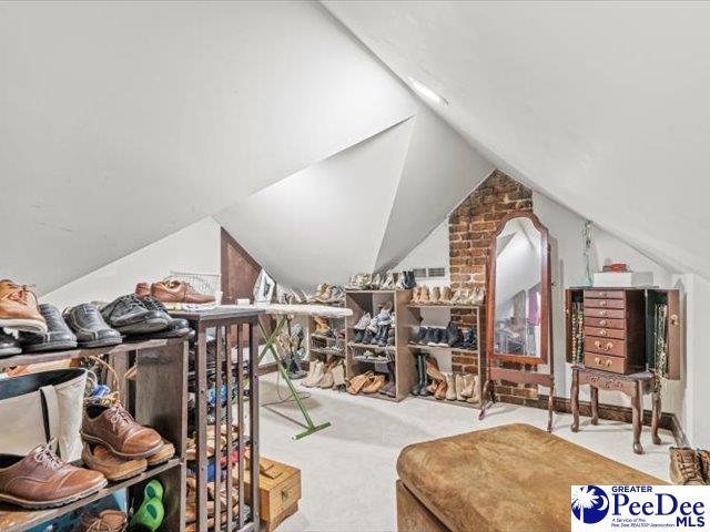 bonus room with lofted ceiling and light colored carpet