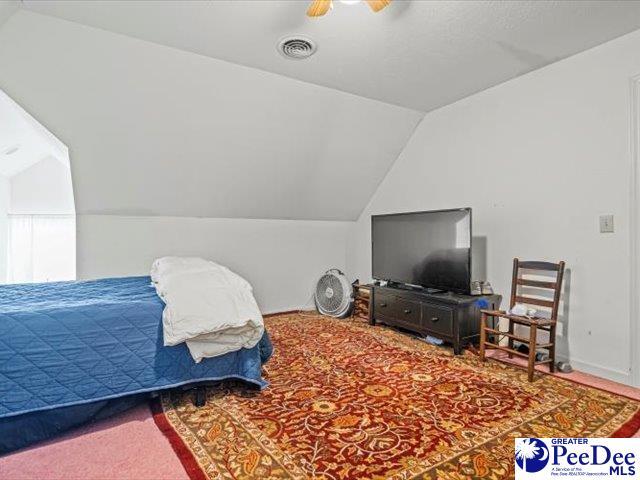 carpeted bedroom with ceiling fan and vaulted ceiling