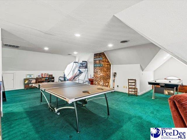 rec room with carpet floors and vaulted ceiling