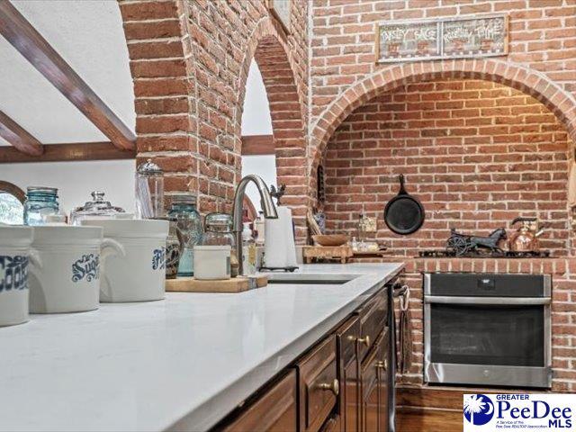 kitchen with sink, beam ceiling, and oven