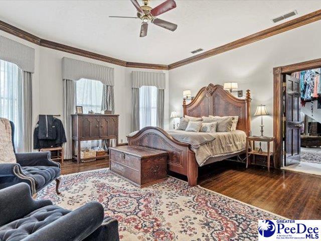 bedroom featuring crown molding, hardwood / wood-style flooring, and ceiling fan