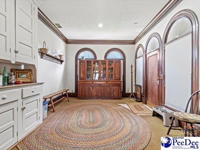 living area with crown molding and light carpet