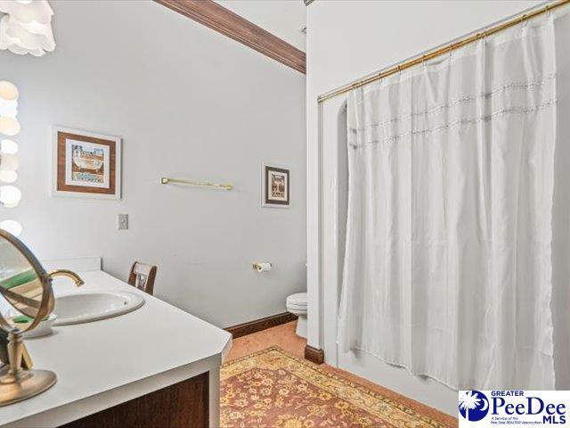 full bathroom featuring crown molding, shower / tub combo with curtain, vanity, and toilet