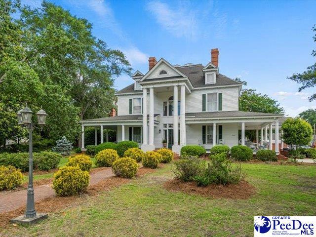 greek revival inspired property featuring a front lawn and covered porch