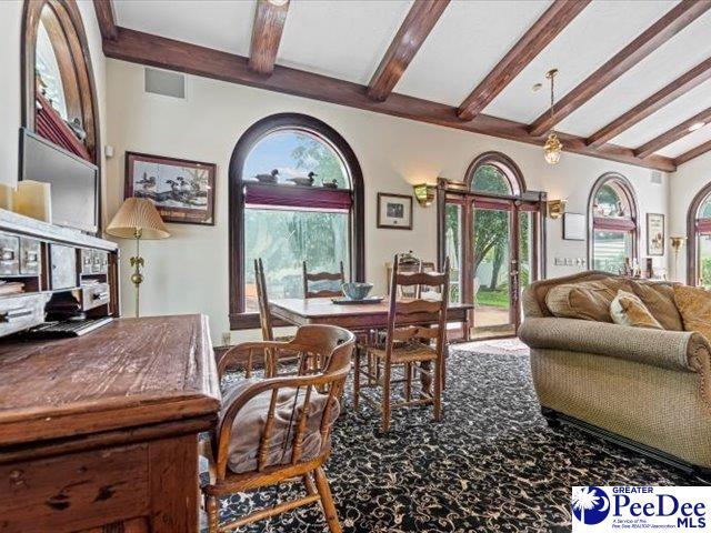 interior space featuring carpet floors, lofted ceiling with beams, and a healthy amount of sunlight