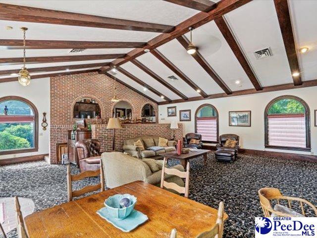 dining space with brick wall and lofted ceiling with beams