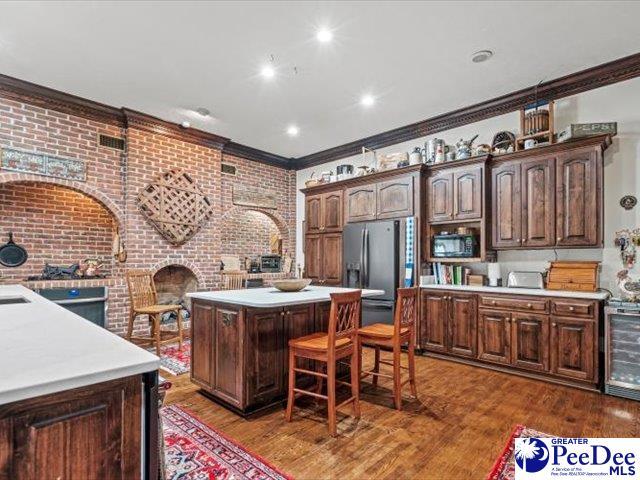 kitchen with dark wood-type flooring, beverage cooler, stainless steel refrigerator with ice dispenser, and a kitchen island