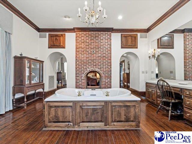 bathroom with ornamental molding, vanity, wood-type flooring, and a tub