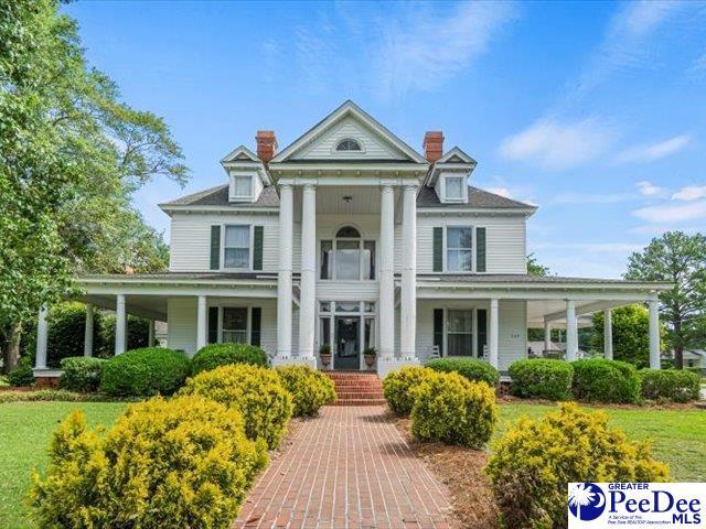 neoclassical home featuring covered porch and a front yard